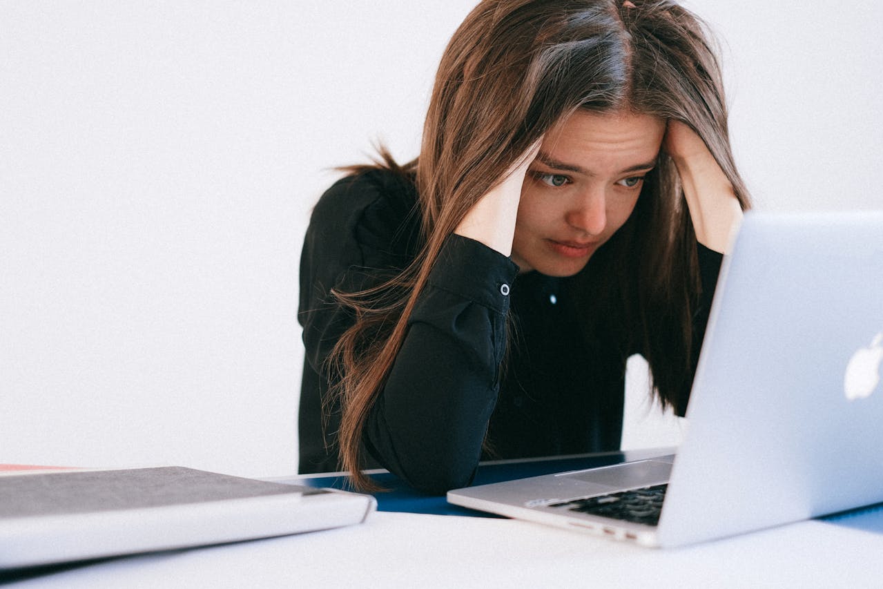 a woman on a laptop that looks like she may be a little stressed. This is to repersent that improving your article content can help reduce cognitive load.